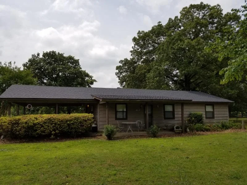 Stone-front single-story home with a broad shingle roof from CAR’s residential portfolio
