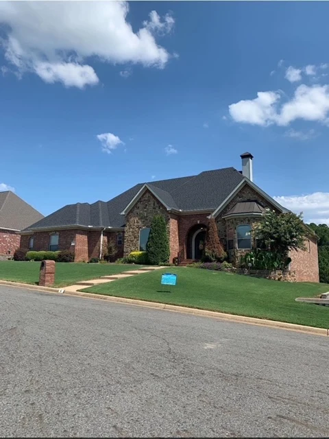 Brick-and-stone home with multiple gables and a dark shingle roof from CAR’s residential portfolio