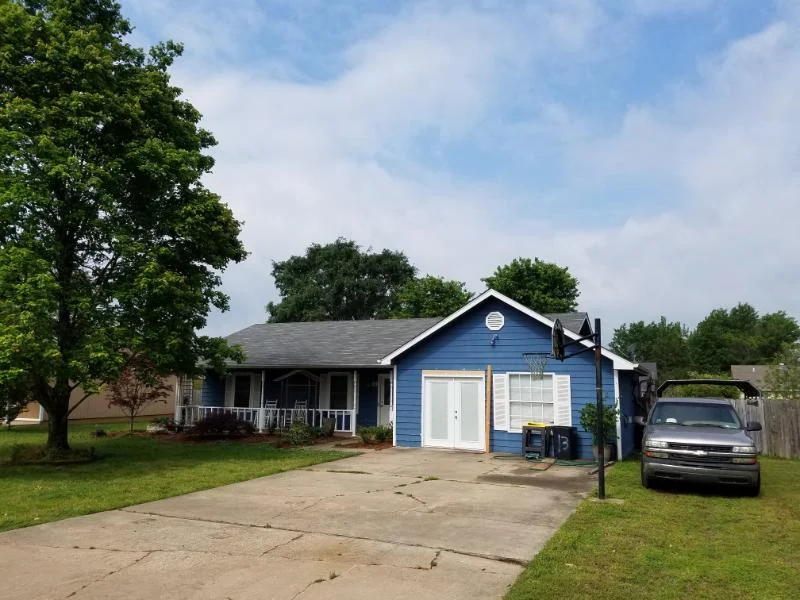 Blue single-story house with a front porch and attached garage from CAR’s residential portfolio