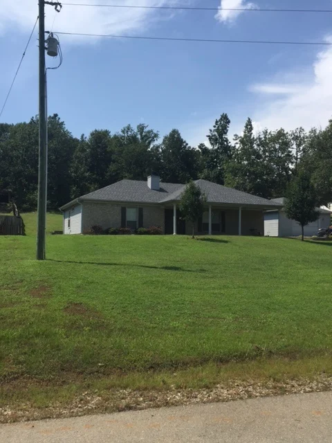Single-story light-colored home with a front porch and a broad lawn from CAR’s residential portfolio