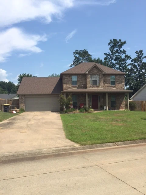 Two-story stone-front home with a covered porch and attached garage from CAR’s residential portfolio